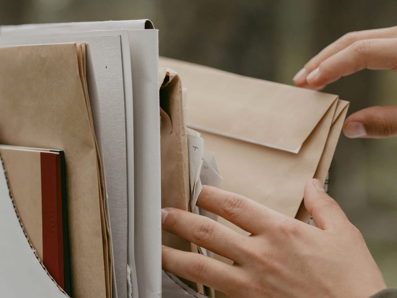 Hände nehmen Unterlagen aus einem Stapel Papiermappen