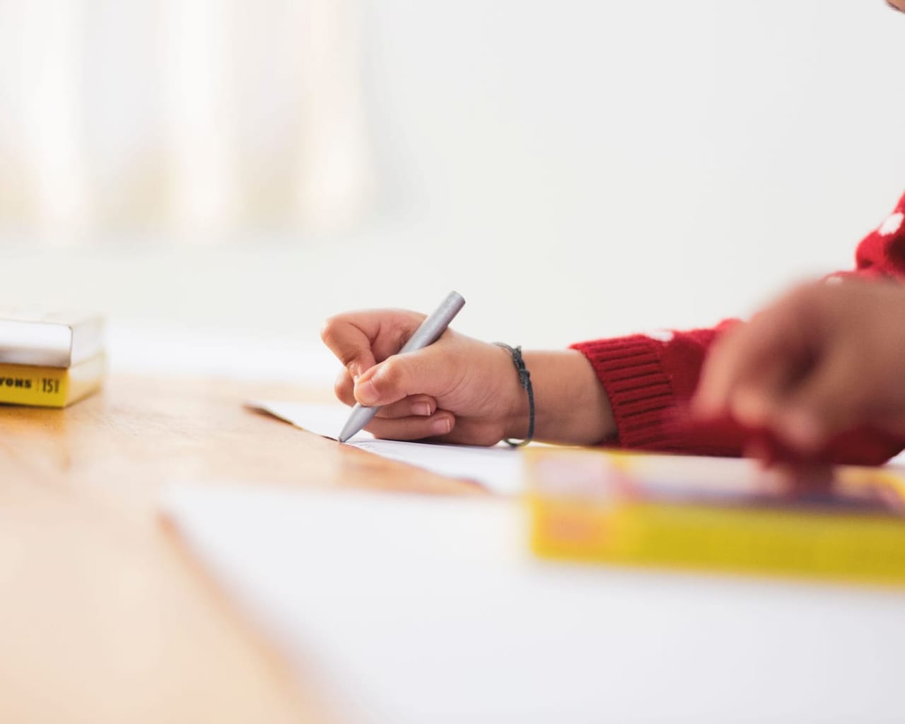 Eine Kinderhand malt mit einem Stift auf einem großen Blatt Papier